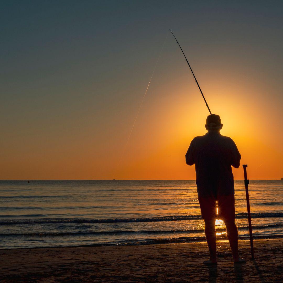 A silhouette of a man fishing in the sunset or sunrise